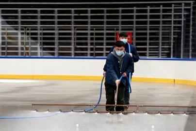 two people spraying an ice rink