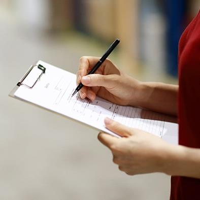 Woman writing on a document that is on a clipboard