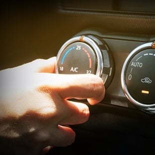 hand adjusting air conditioning and heating temperature on car console