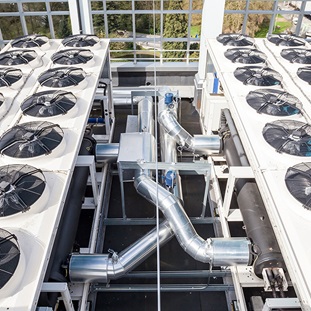 series of air conditioning units with fans on a rooftop