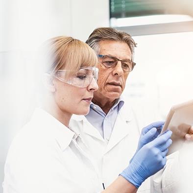 man and woman in lab coats looking at a smart tablet
