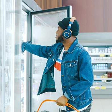 man reaching into a fridge in a grocery store