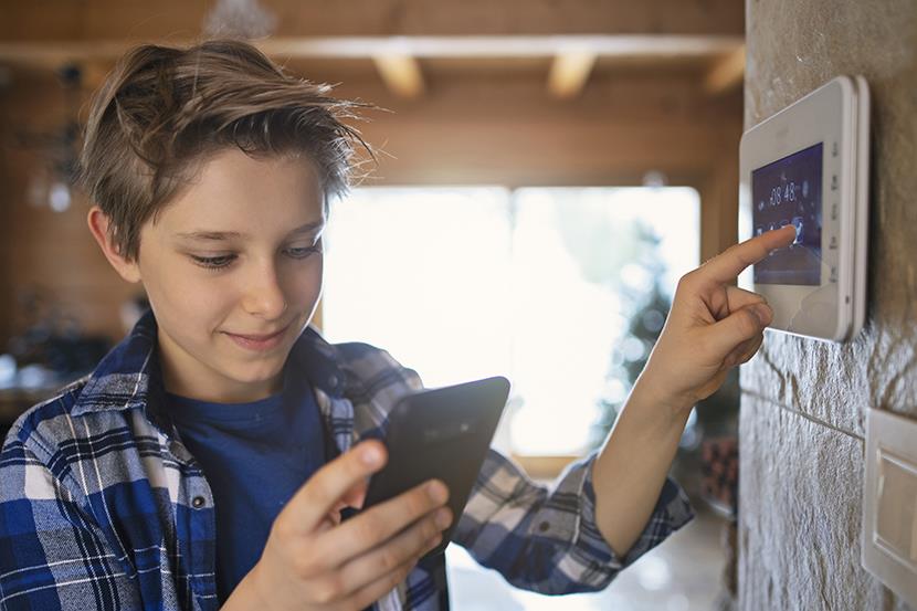 Child looking at phone and touching thermostat