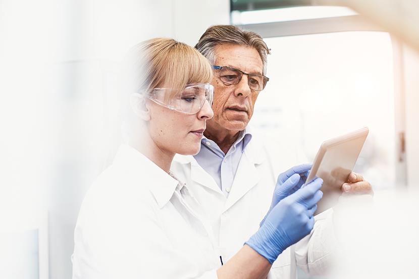 man and woman in lab coats looking at a smart tablet 1 5 5
