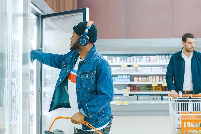 man reaching into refrigerated unit at grocery store