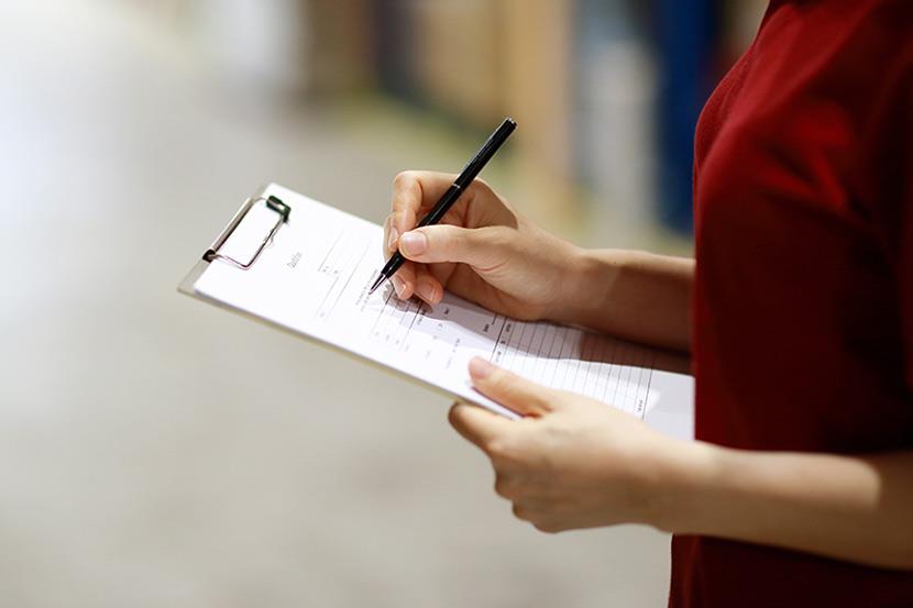 Woman writing on a document that is on a clipboard