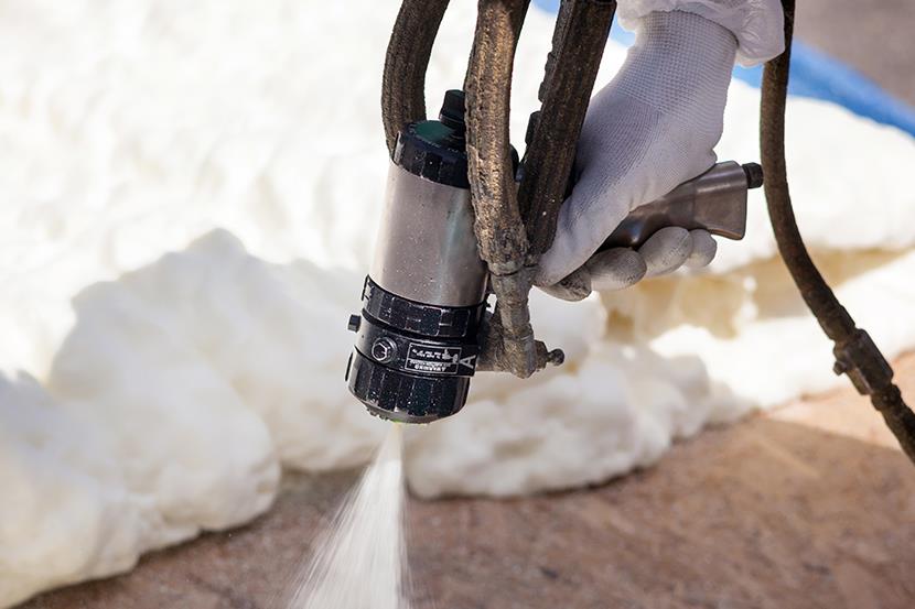 closeup of hand holding foam insulation sprayer spraying foam